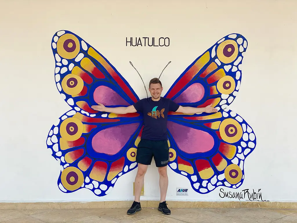 Huatulco Airport (Airport Code: HUX) - Andy in front of butterfly mural